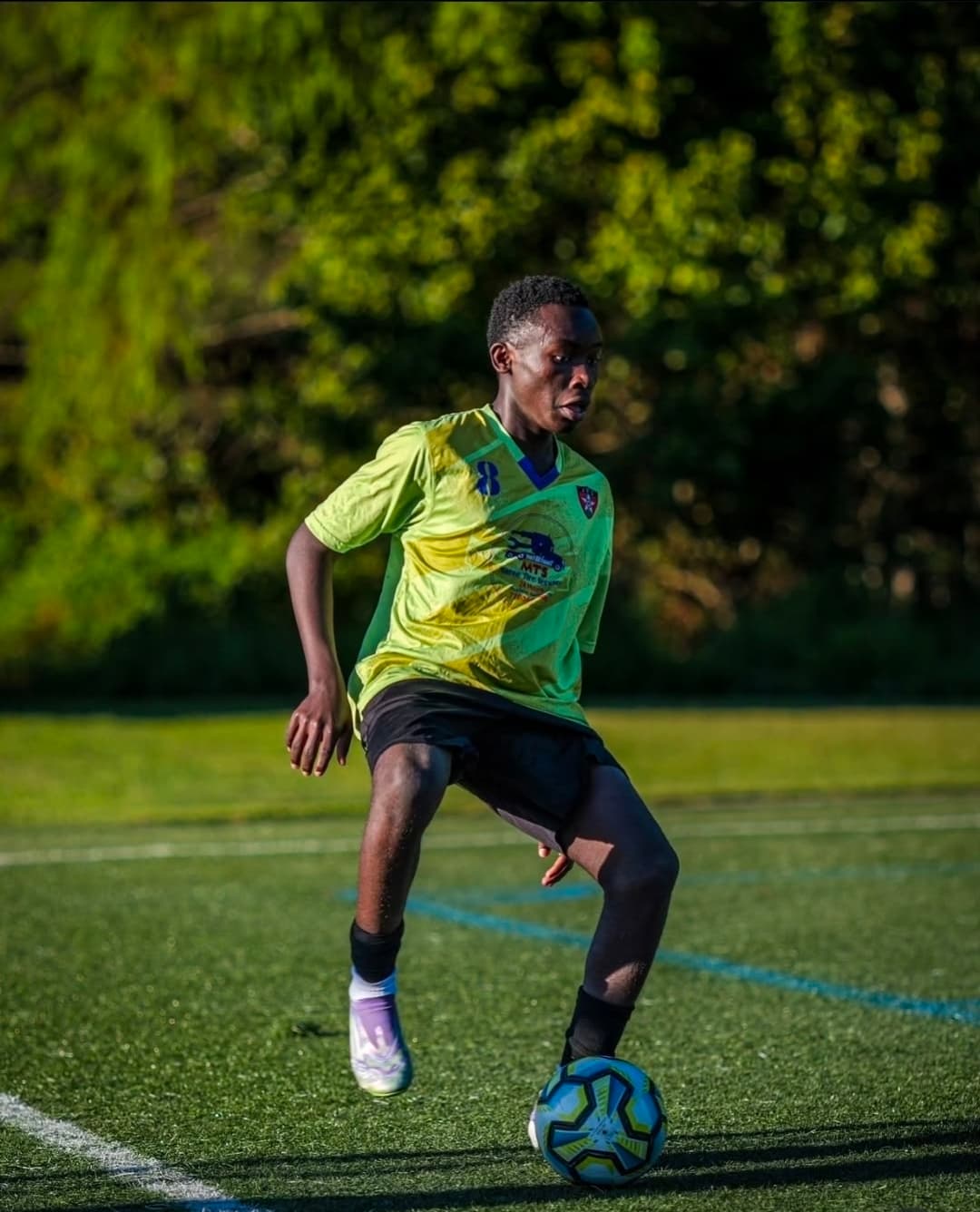 A young JFC player in green dribbling the ball
