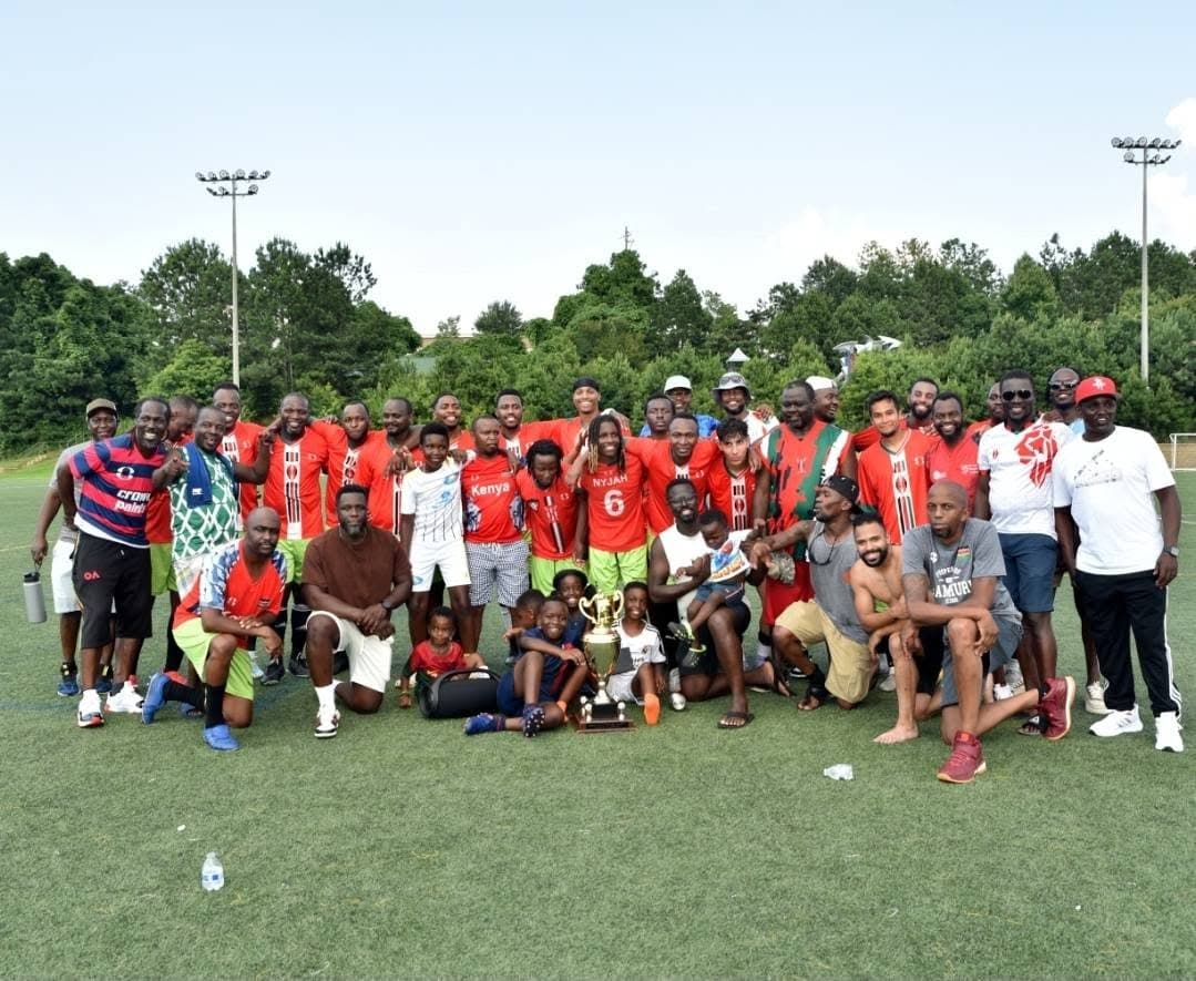 Jamhuri FC players, staff and children gathered around the CASL Georgia State Championship trophy
