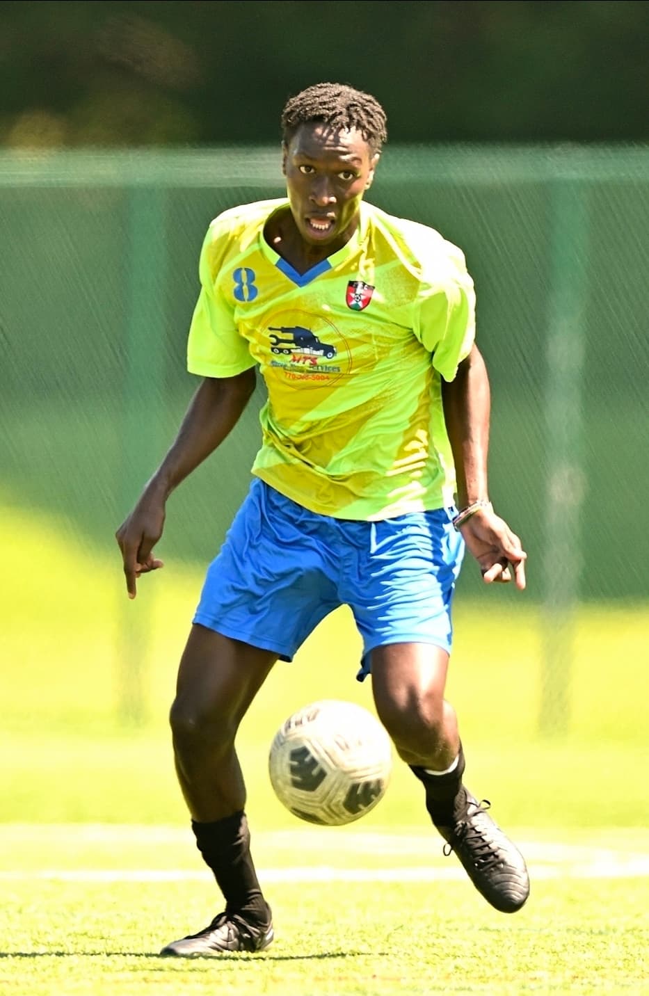 A JFC midfielder in green on the ball, looking up