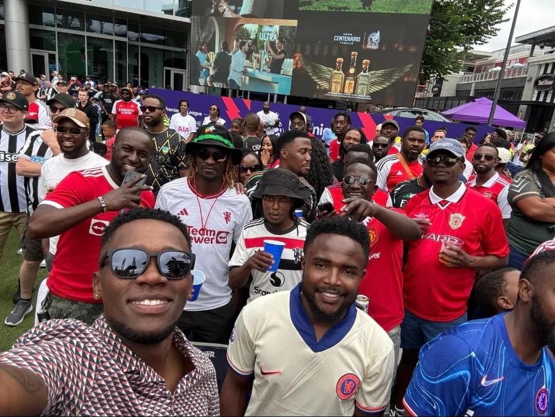 A selfie in front of a crowd of friends in football shirts at an outdoor Premier League watch party