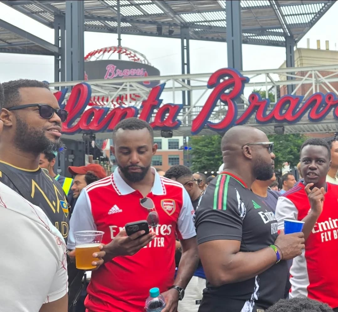 Friends in Arsenal shirts in the crowd beneath the Atlanta Braves sign