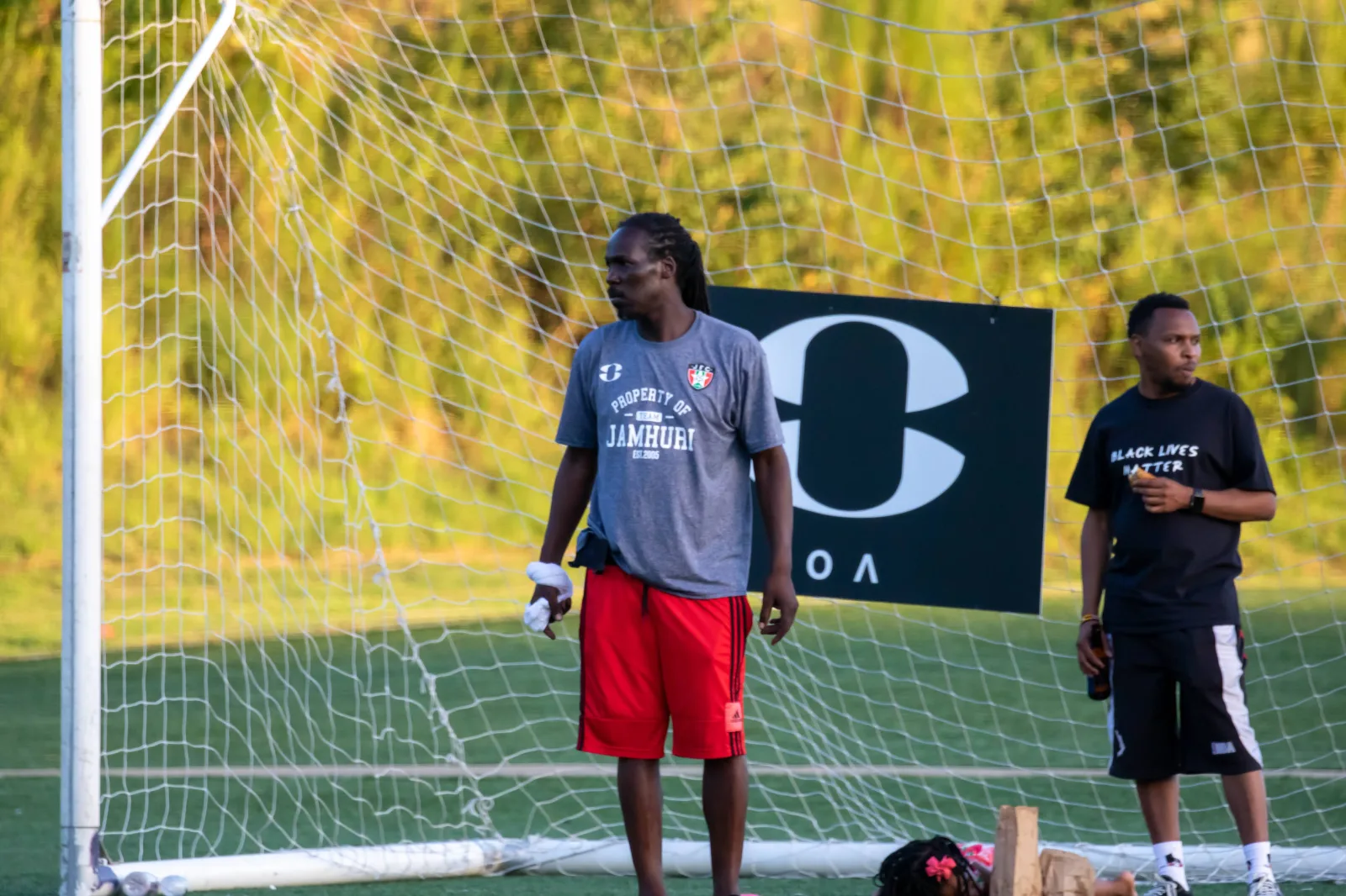 Two coaches stand by the goal watching the game