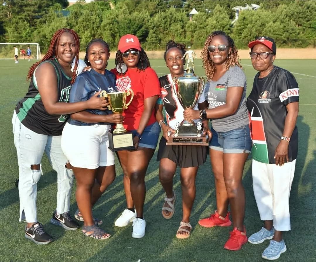 Six women in Kenya colours holding trophies on the pitch