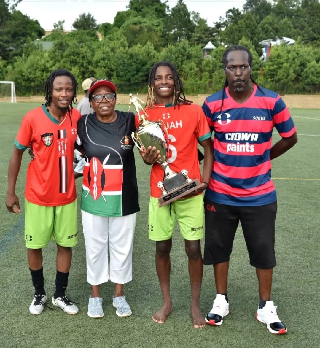 A family and players in Kenya colours posing with a trophy on the pitch
