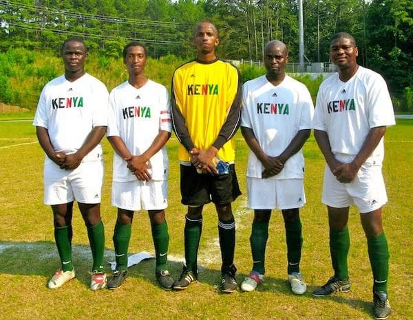 Five players in white Kenya shirts and a keeper in yellow lined up on the pitch