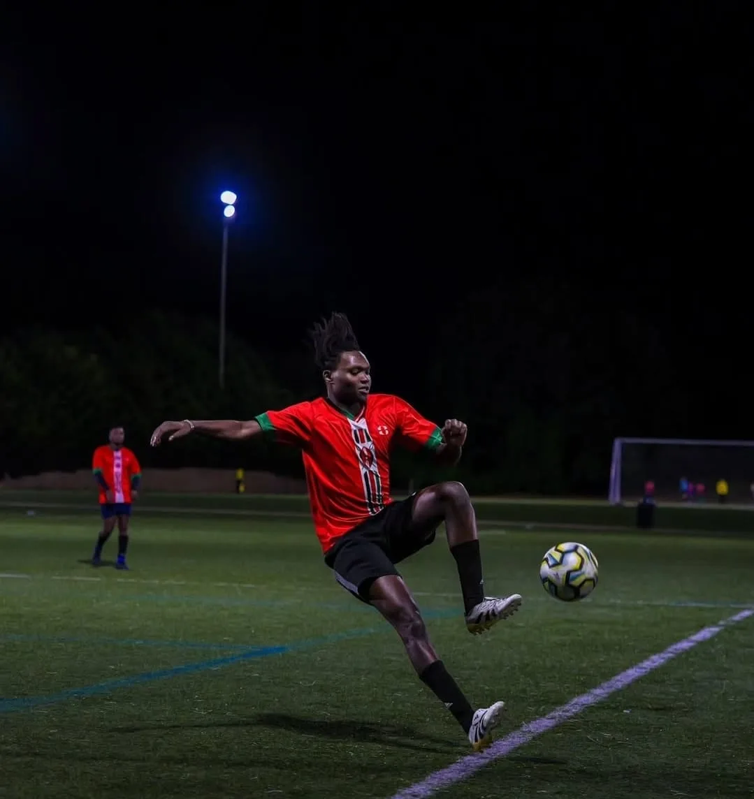 A JFC player in red stretching to volley the ball under the floodlights