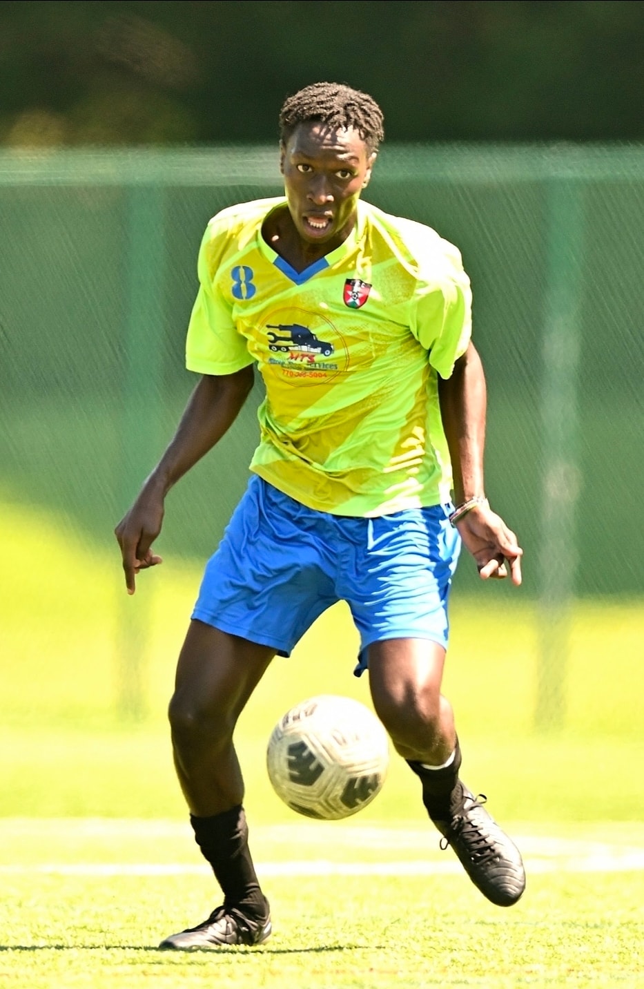 A JFC midfielder in green on the ball, looking up
