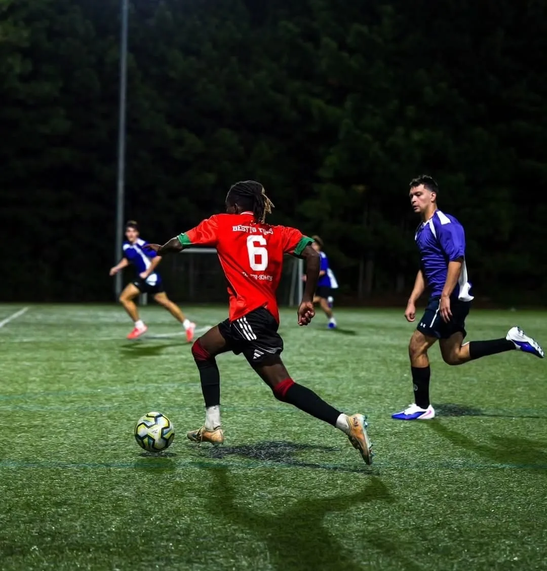 JFC's number 6 driving forward with the ball as defenders in purple close in